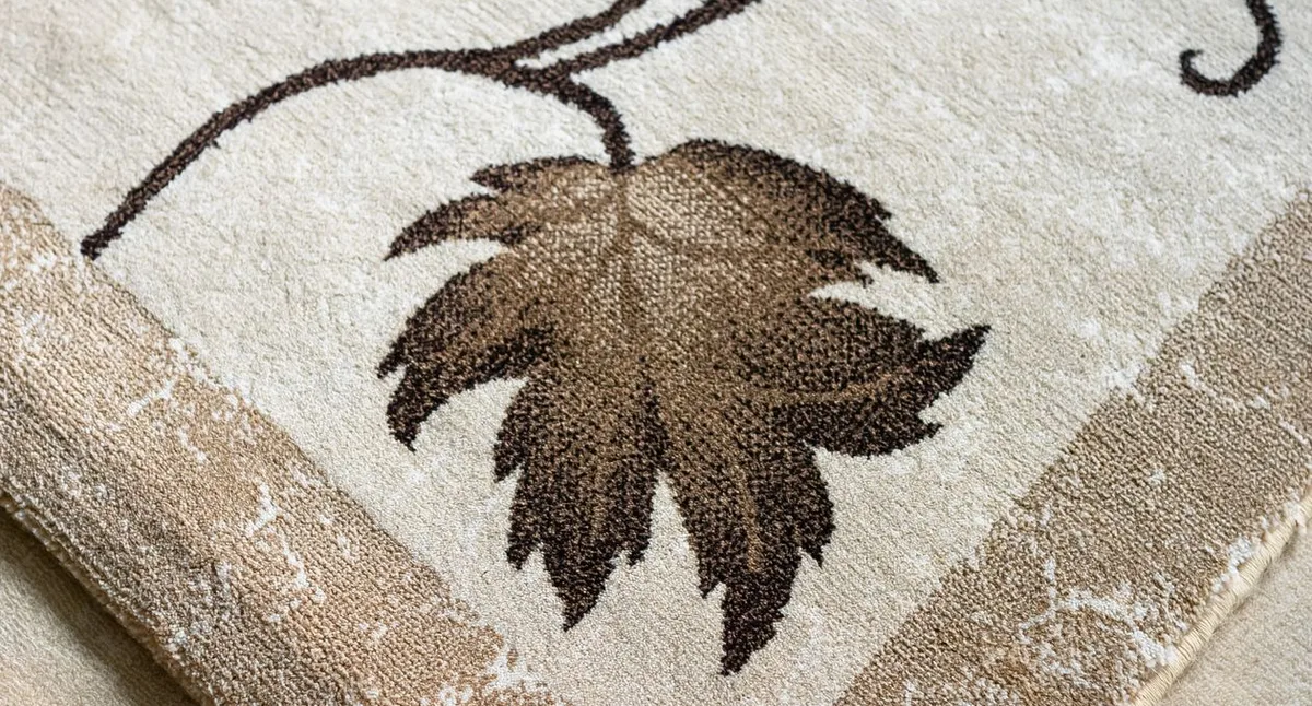 Närbild av en beige matta med brunt bladmönster